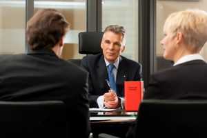 Mature lawyer or notary with clients in his office in a meeting