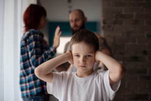 A child covering his ears during his parents' argument
