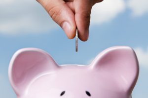 A coin being put into a piggy bank 