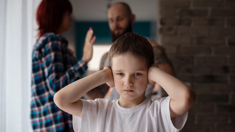 A child covering his ears during his parents' argument