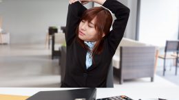 Office employee stretching at her desk