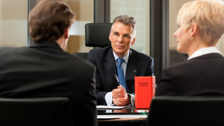 Mature lawyer or notary with clients in his office in a meeting