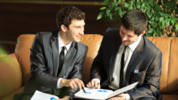 Image of two young businessmen discussing project at meeting