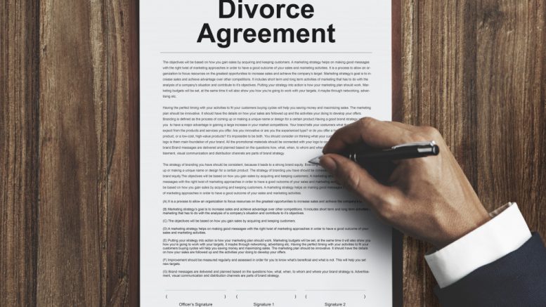 Man signing a divorce agreement on a table.