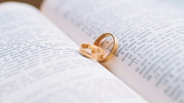 Two Gold-colored Wedding Bands on Book Page